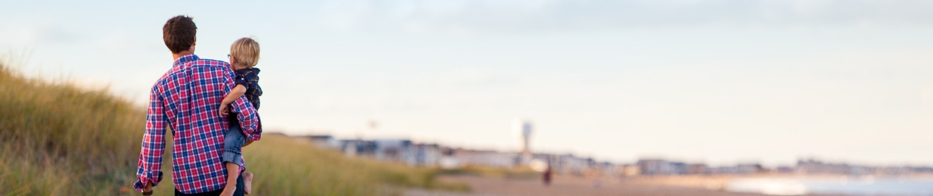 Een man met zijn zoon op het strand kijkend naar de stad